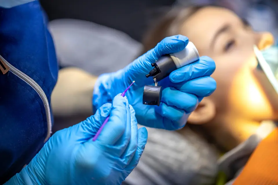 Dental professional in blue gloves preparing a treatment